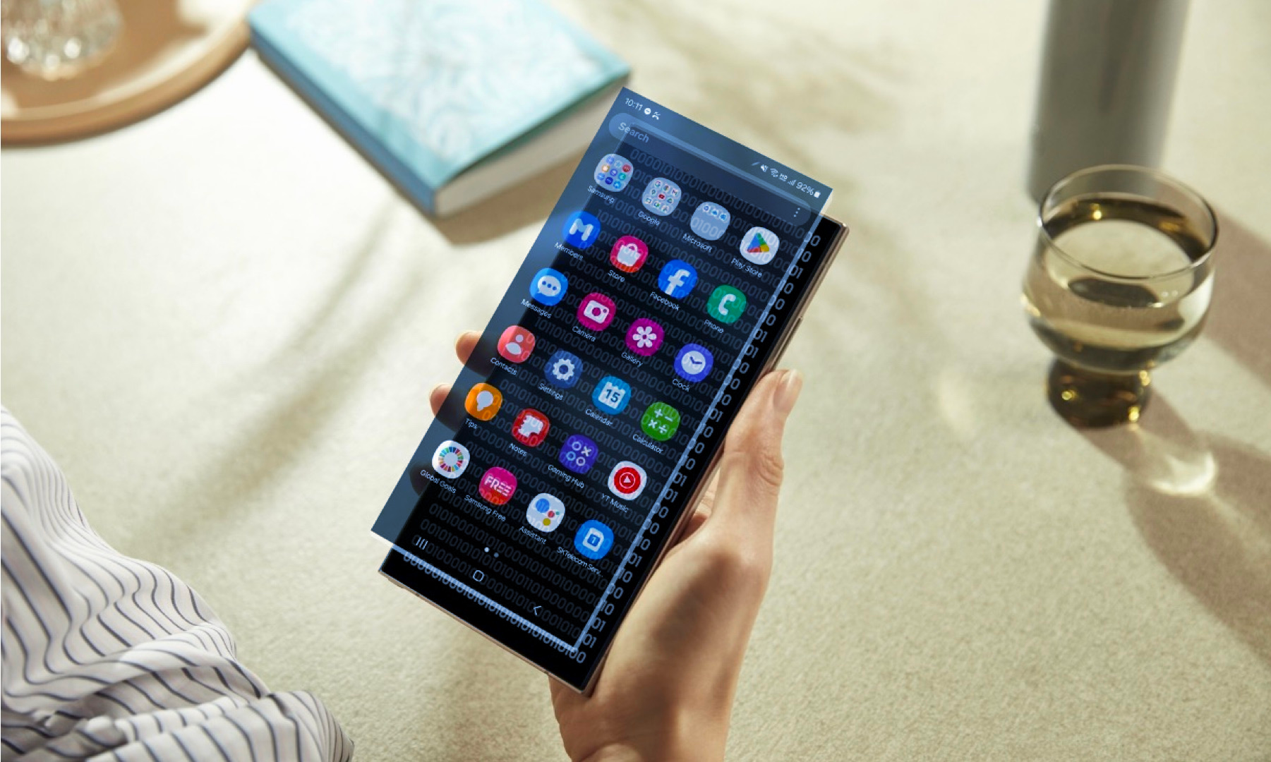 Personne tenant un appareil Samsung avec un code binaire sous une superposition de l'écran d'application.